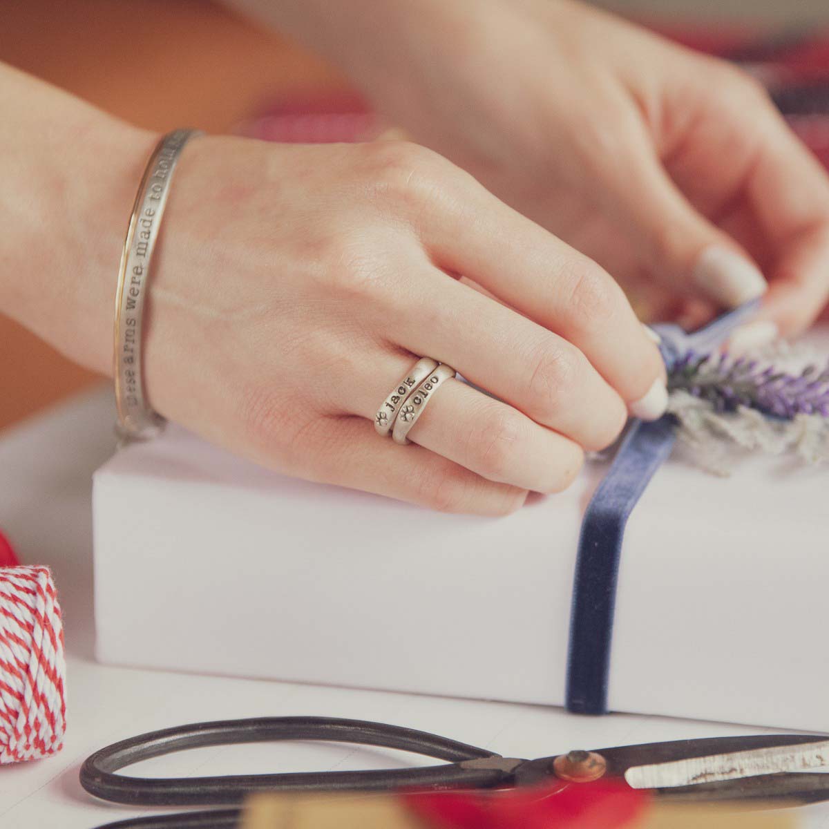 Woman wearing her furry footprint sterling silver stacking ring personalized with a pet name