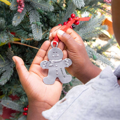 Gingerbread boy ornament  hand-molded and cast in fine pewter hung from a sheer red ribbon with a personalized word being placed on Christmas tree