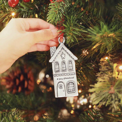 hand hanging a personalized Heart of the Home pewter ornament on a Christmas tree