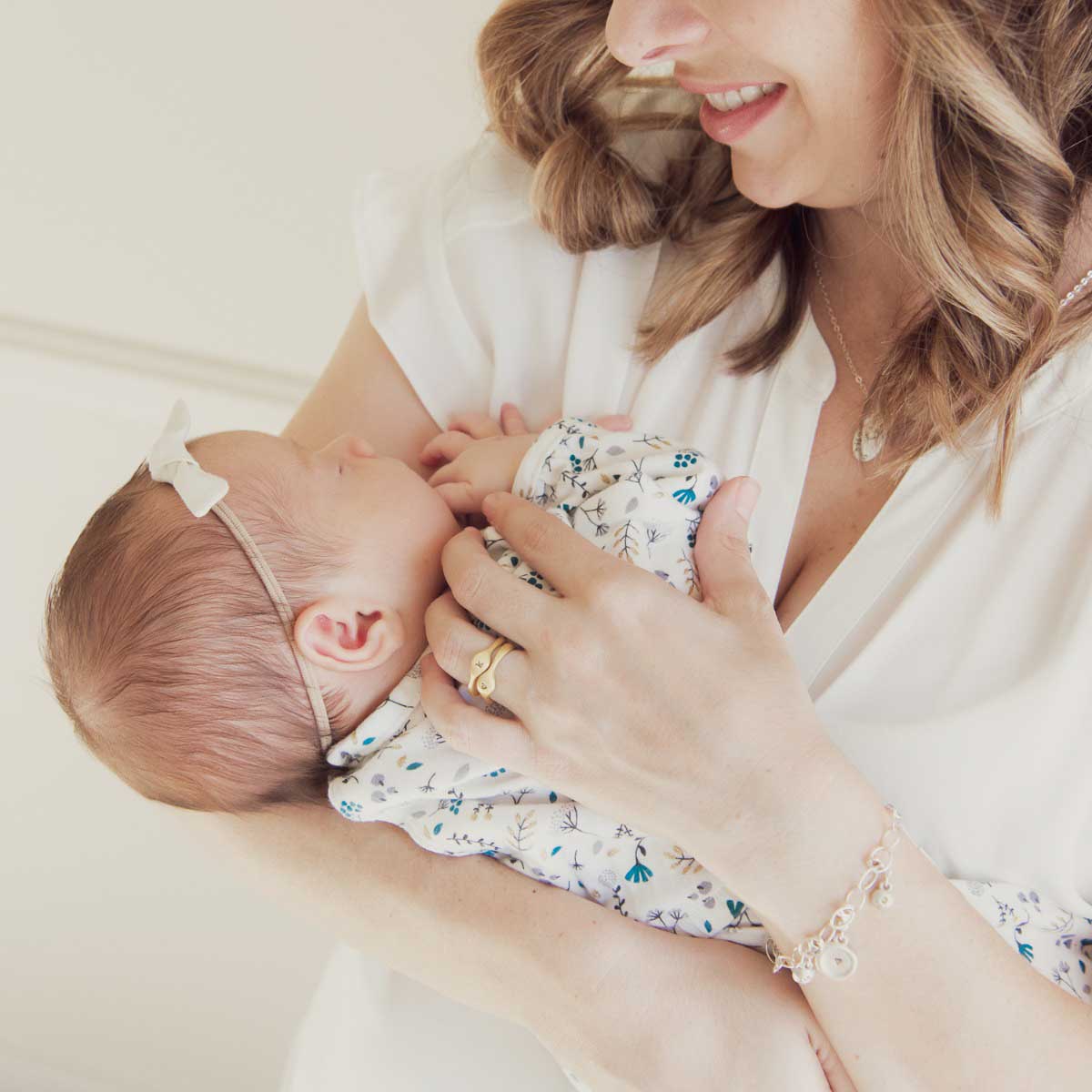 Mom wearing her Initial stacking ring handcrafted and cast in 10k yellow gold then hand-stamped with an initial holding her baby