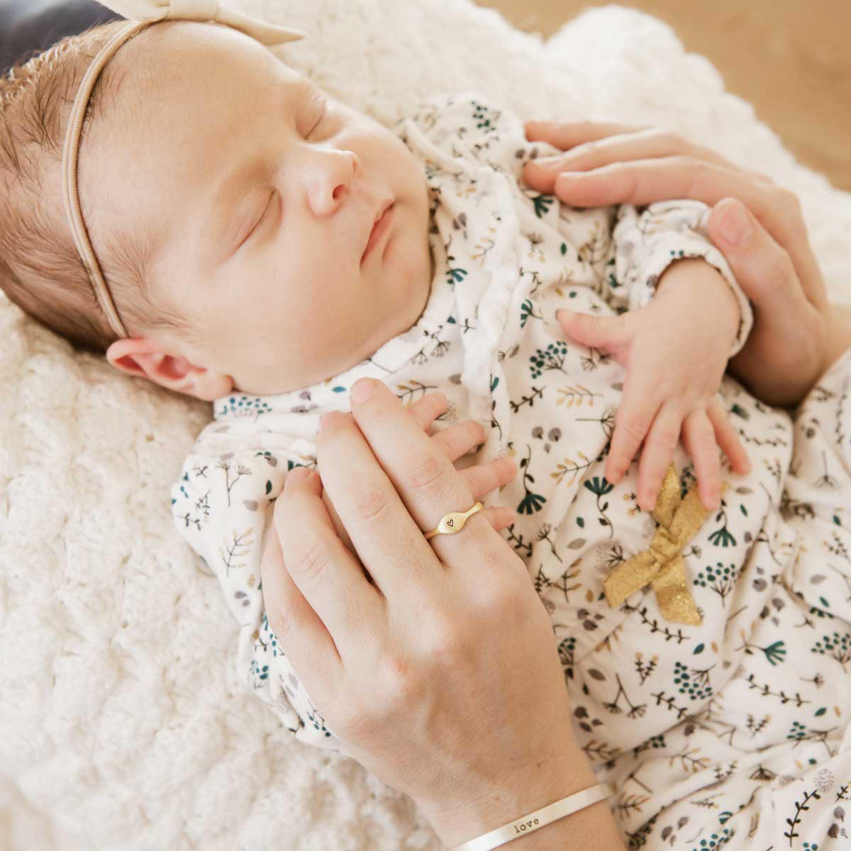 Mom wearing her Initial stacking ring handcrafted and cast in 10k yellow gold then hand-stamped with an initial holding her baby