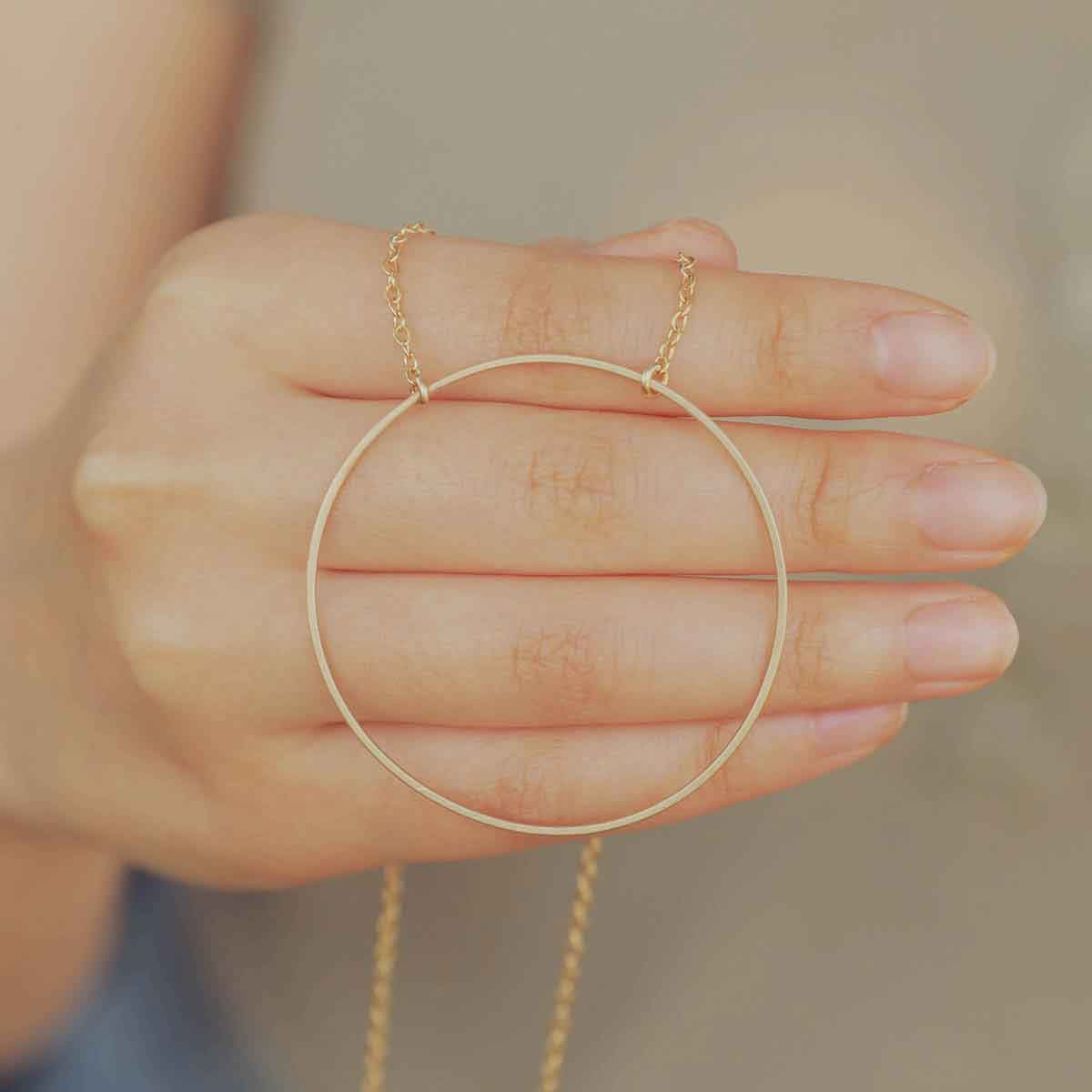 Woman wearing a gold filled It All Matters Circle Necklace in her living room