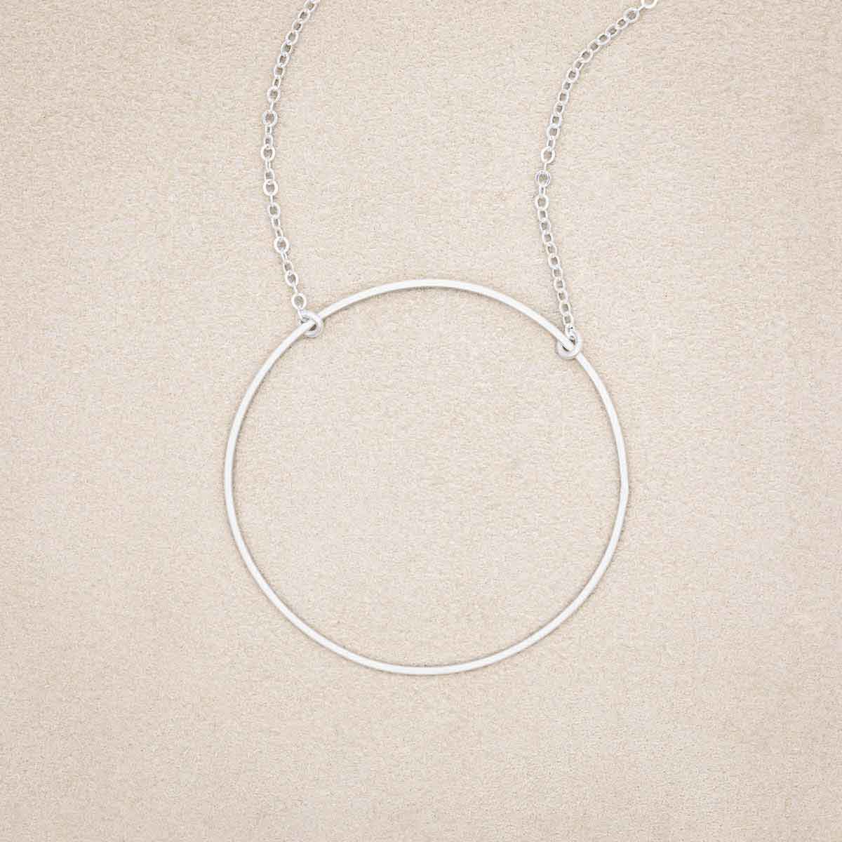 A sterling silver It All Matters Circle Necklace, on beige background
