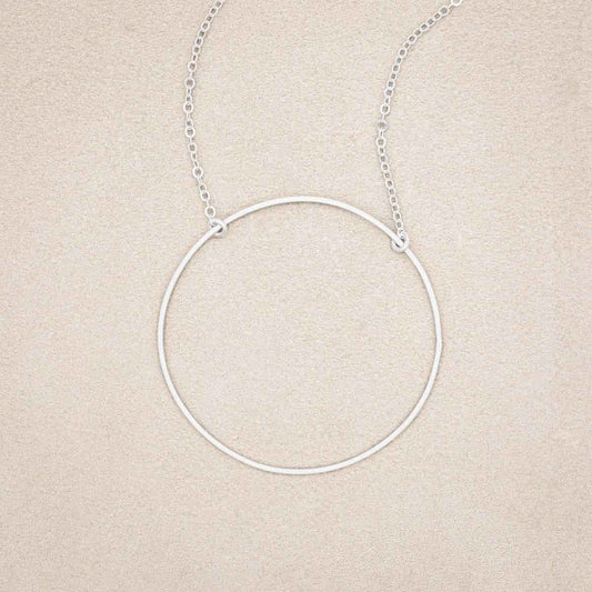 A sterling silver It All Matters Circle Necklace, on beige background
