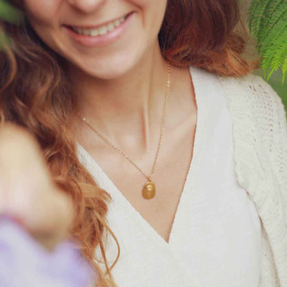 girl holding a gold plated January birth flower necklace with an 18" gold filled link chain