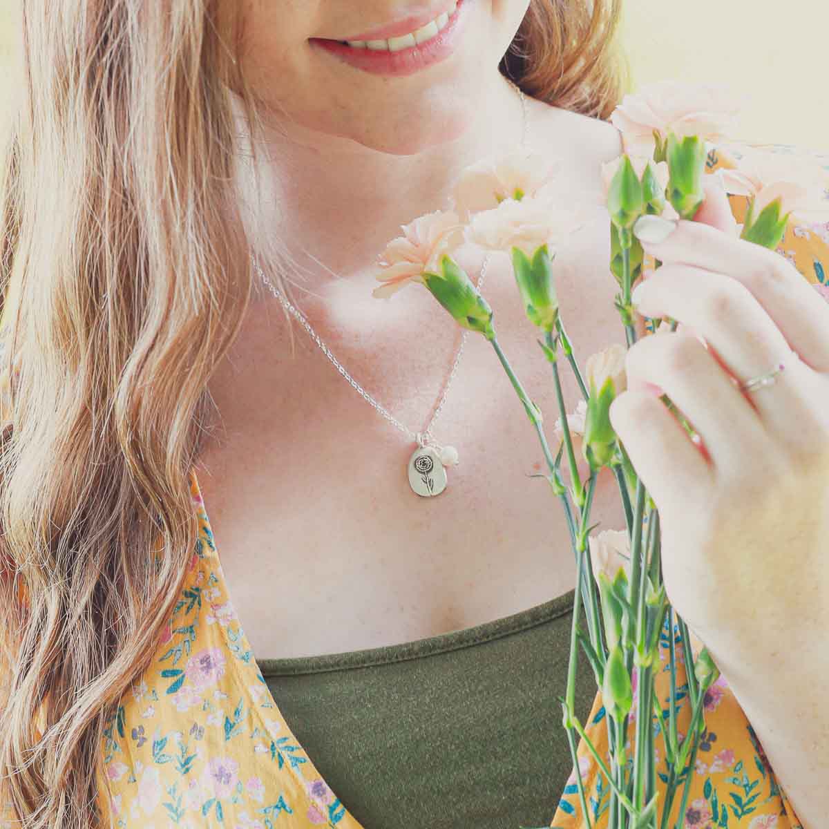 Girl wearing her January birth flower necklace handcrafted in sterling silver with a special birth month charm strung with a vintage freshwater pearl