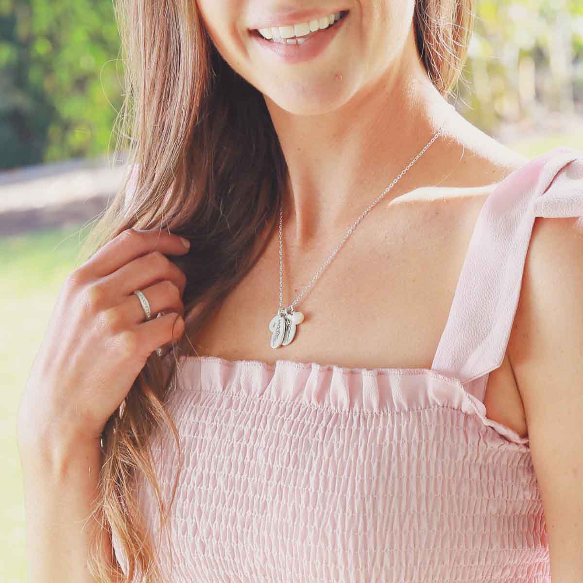 Girl wearing her July birth flower necklace handcrafted in sterling silver with a special birth month charm strung with a vintage freshwater pearl