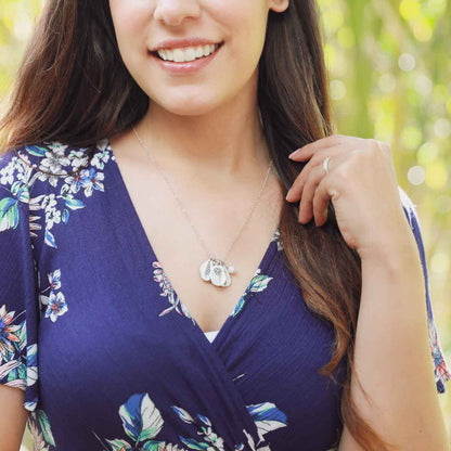 Girl wearing her July birth flower necklace handcrafted in sterling silver with a special birth month charm strung with a vintage freshwater pearl