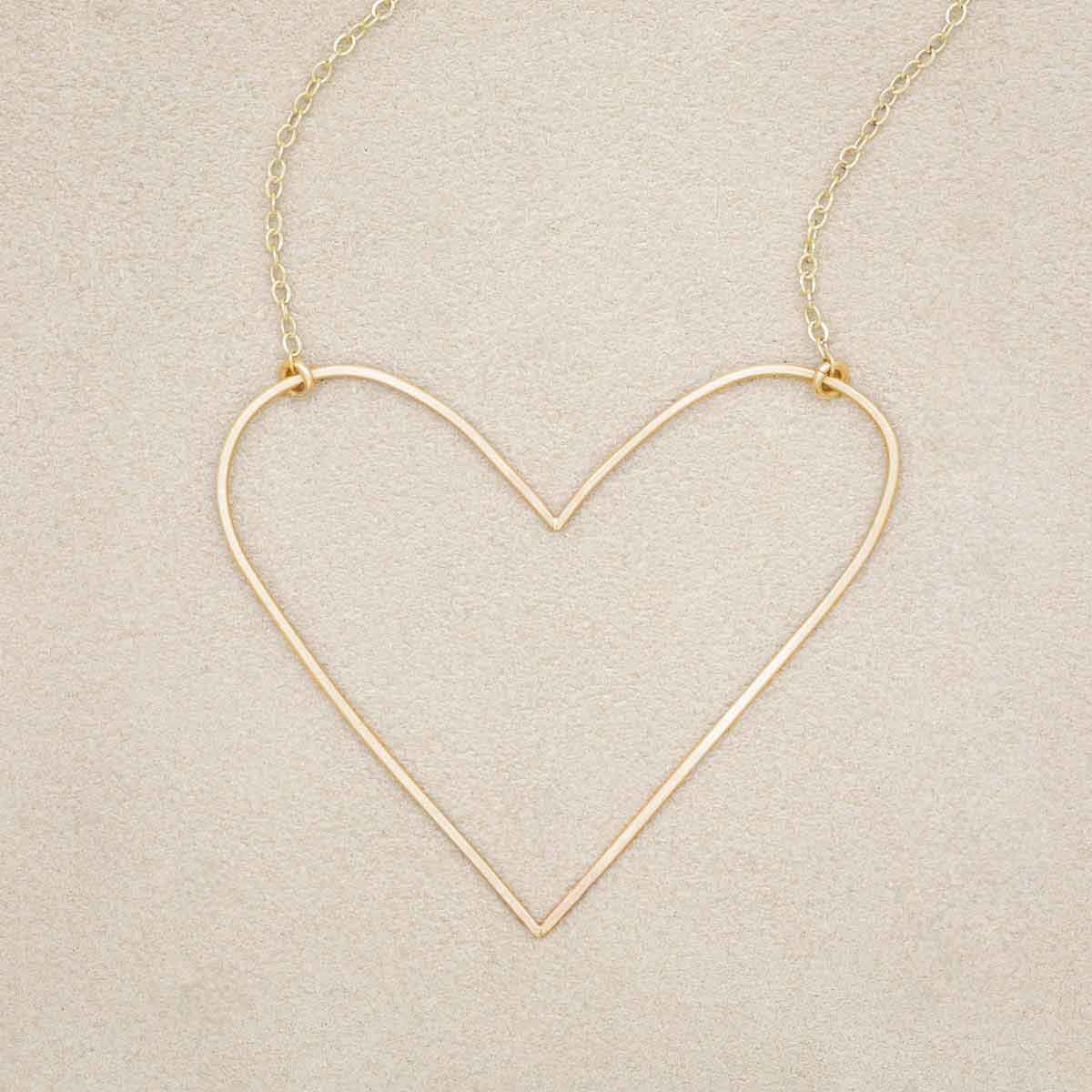 A gold filled Large Peaceful Heart Necklace, on beige background