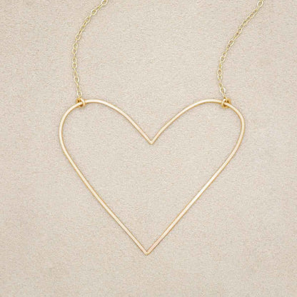 A gold filled Large Peaceful Heart Necklace, on beige background