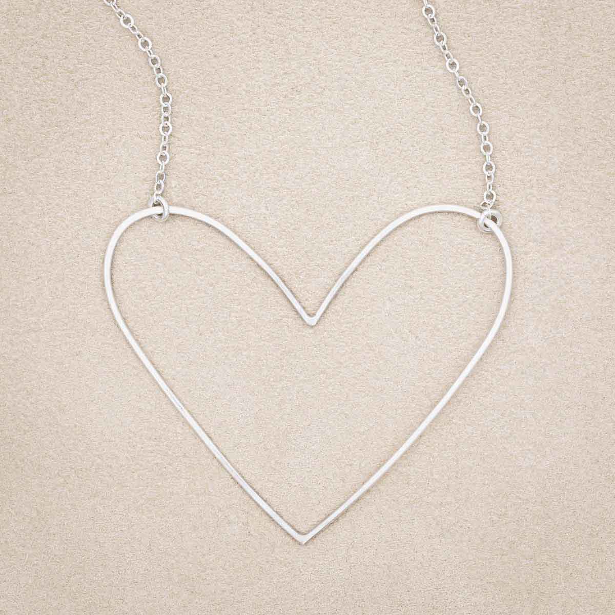 A sterling silver Large Peaceful Heart Necklace, on beige background