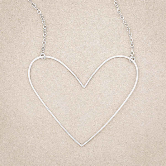 A sterling silver Large Peaceful Heart Necklace, on beige background