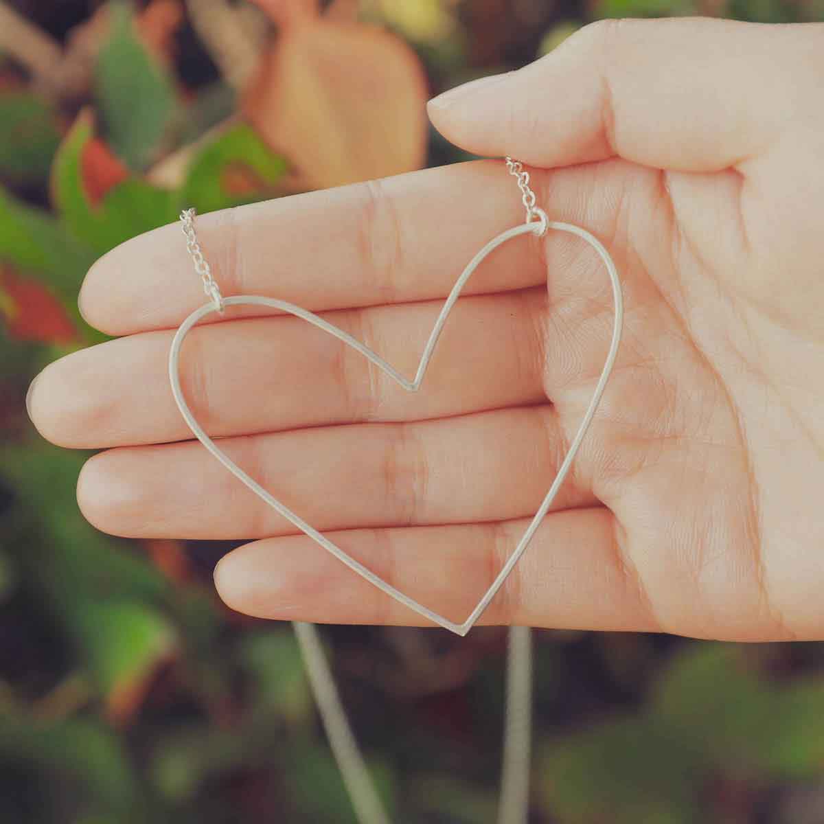 A sterling silver Large Peaceful Heart Necklace on wood floral background