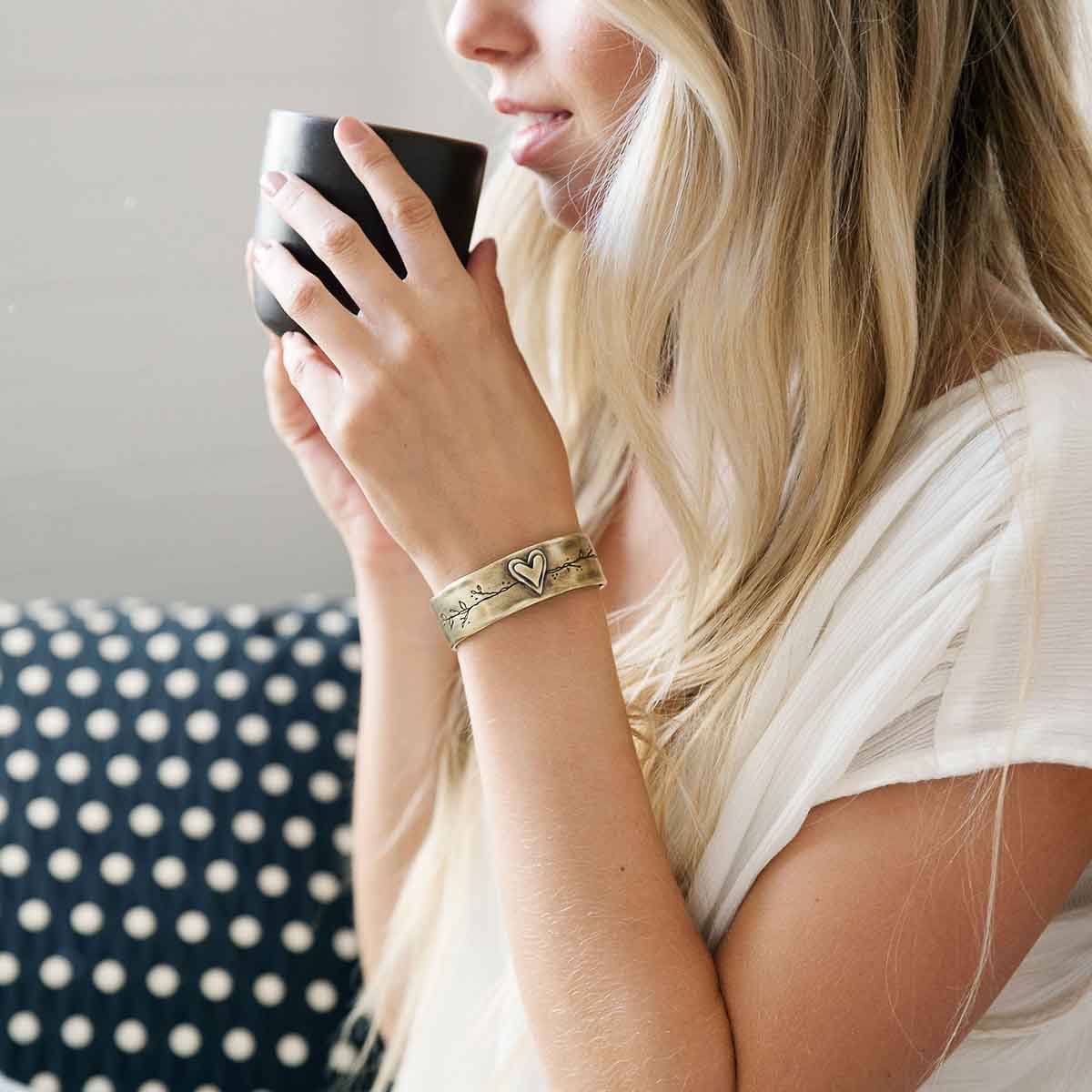 Girl wearing her handcrafted bronze-plated let love grow cuff while drinking tea