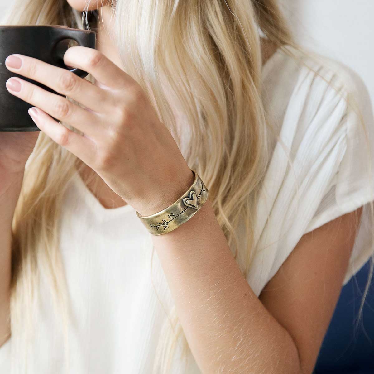 Girl showing her handcrafted bronze-plated let love grow cuff