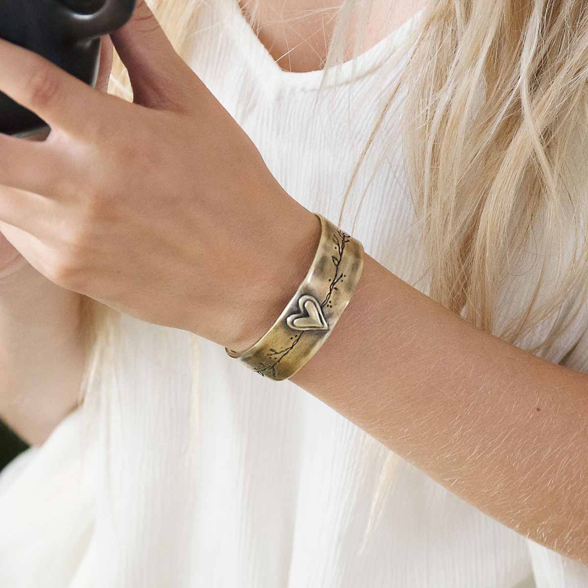 Girl wearing her handcrafted bronze-plated let love grow cuff