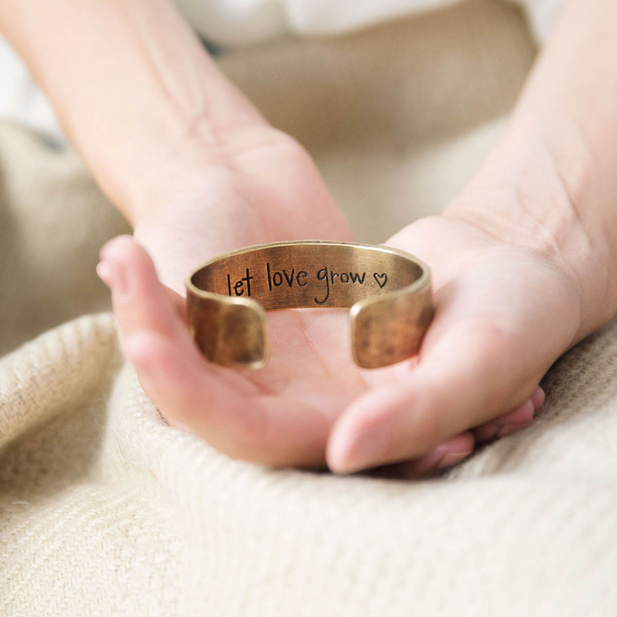 Engraved bronze let love grow cuff on display