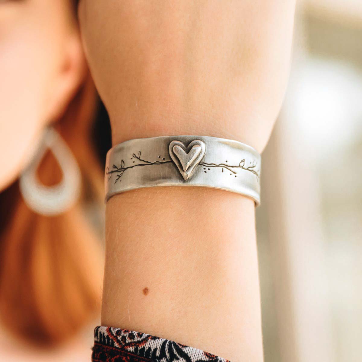 Girl showing her handcrafted pewter let love grow cuff