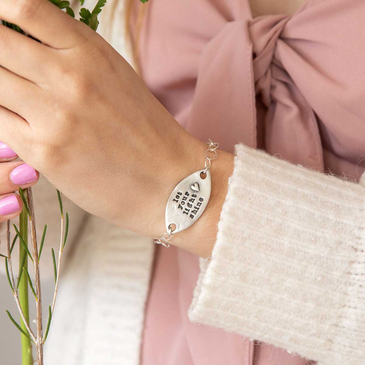 Girl holding engraved let your light shine pewter bracelet with a matte brushed finish