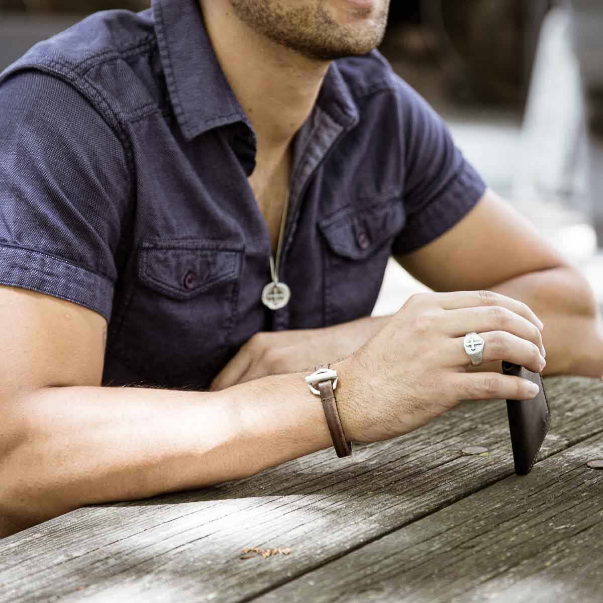 Man wearing Life Forever bracelet handcrafted in water buffalo brown leather and a sterling silver toggle closure along with other sterling silver jewelry