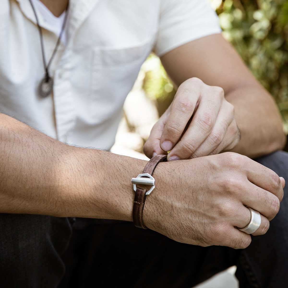 Man wearing Life Forever bracelet handcrafted in water buffalo brown leather and a sterling silver toggle closure along with other sterling silver jewelry