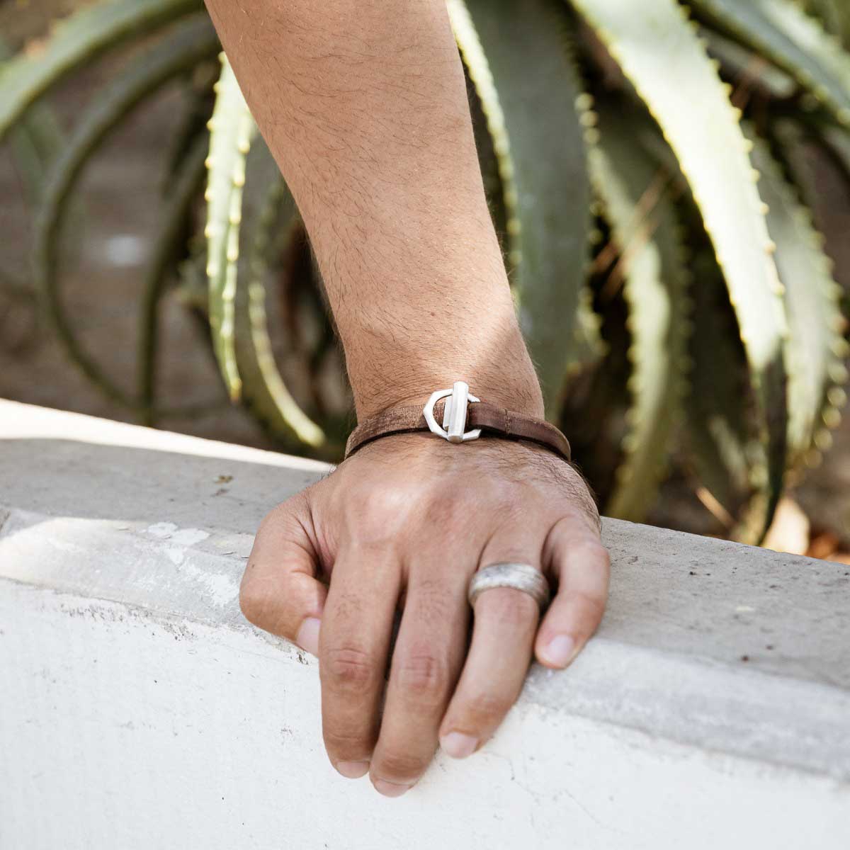 Man wearing Life Forever bracelet handcrafted in water buffalo brown leather and a sterling silver toggle closure along with other sterling silver jewelry