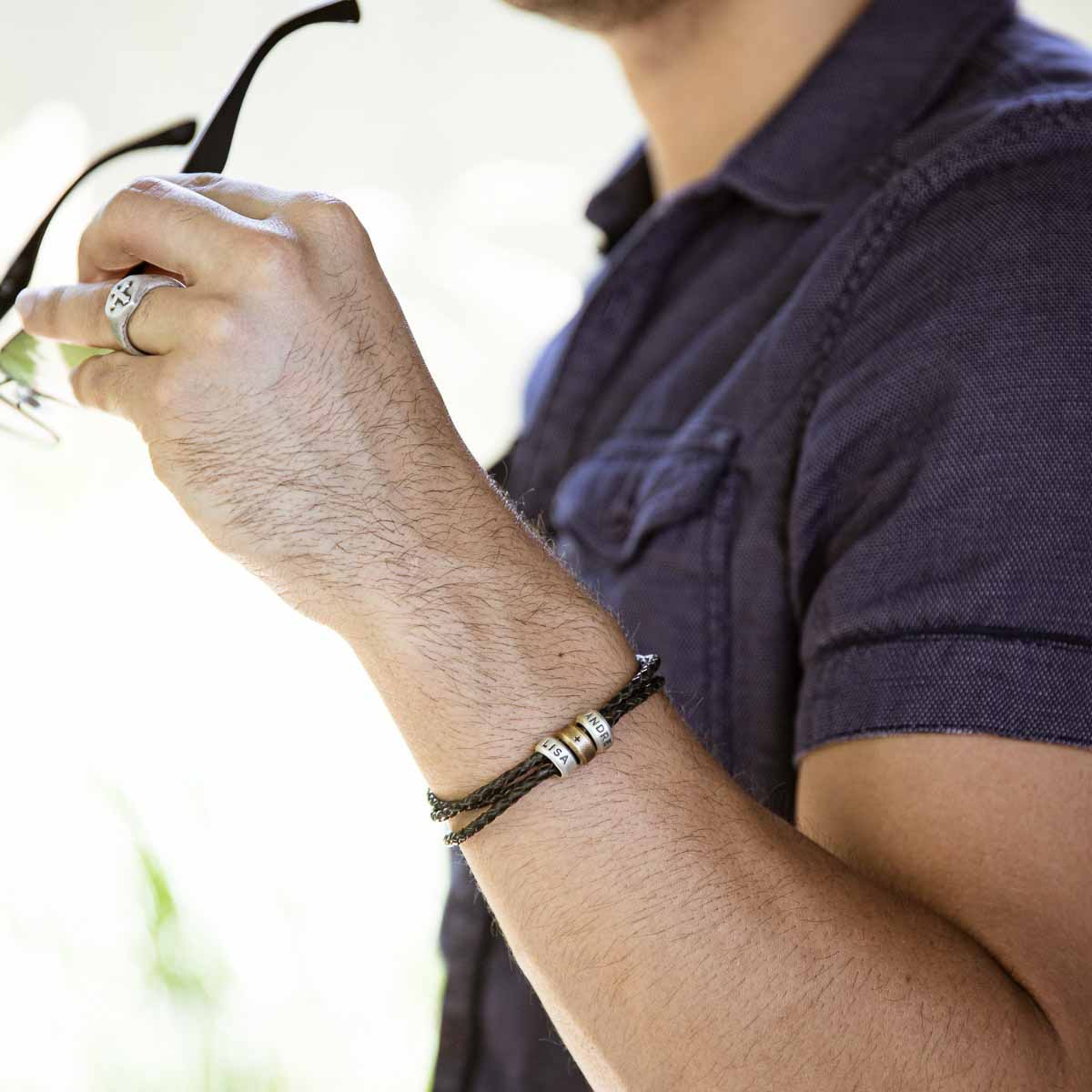 Man wearing Limitless Leather bracelet handcrafted with black bolo leather cord and choice of personalized sterling silver and bronze limitless rings