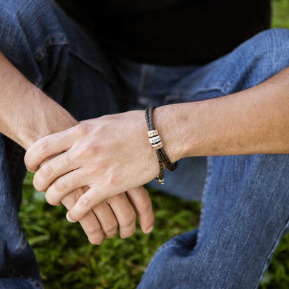 Man wearing Limitless Leather bracelet handcrafted with black bolo leather cord and choice of personalized sterling silver and bronze limitless rings