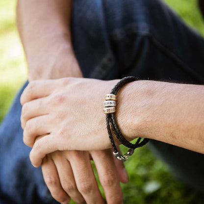 Man wearing Limitless Leather bracelet handcrafted with black bolo leather cord and choice of personalized sterling silver and bronze limitless rings