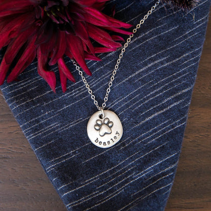 Furry footprint necklace handcrafted in sterling silver with a paw engraved and personalized with a pet's name