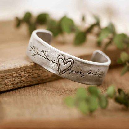 pewter let love grow cuff sitting on wood