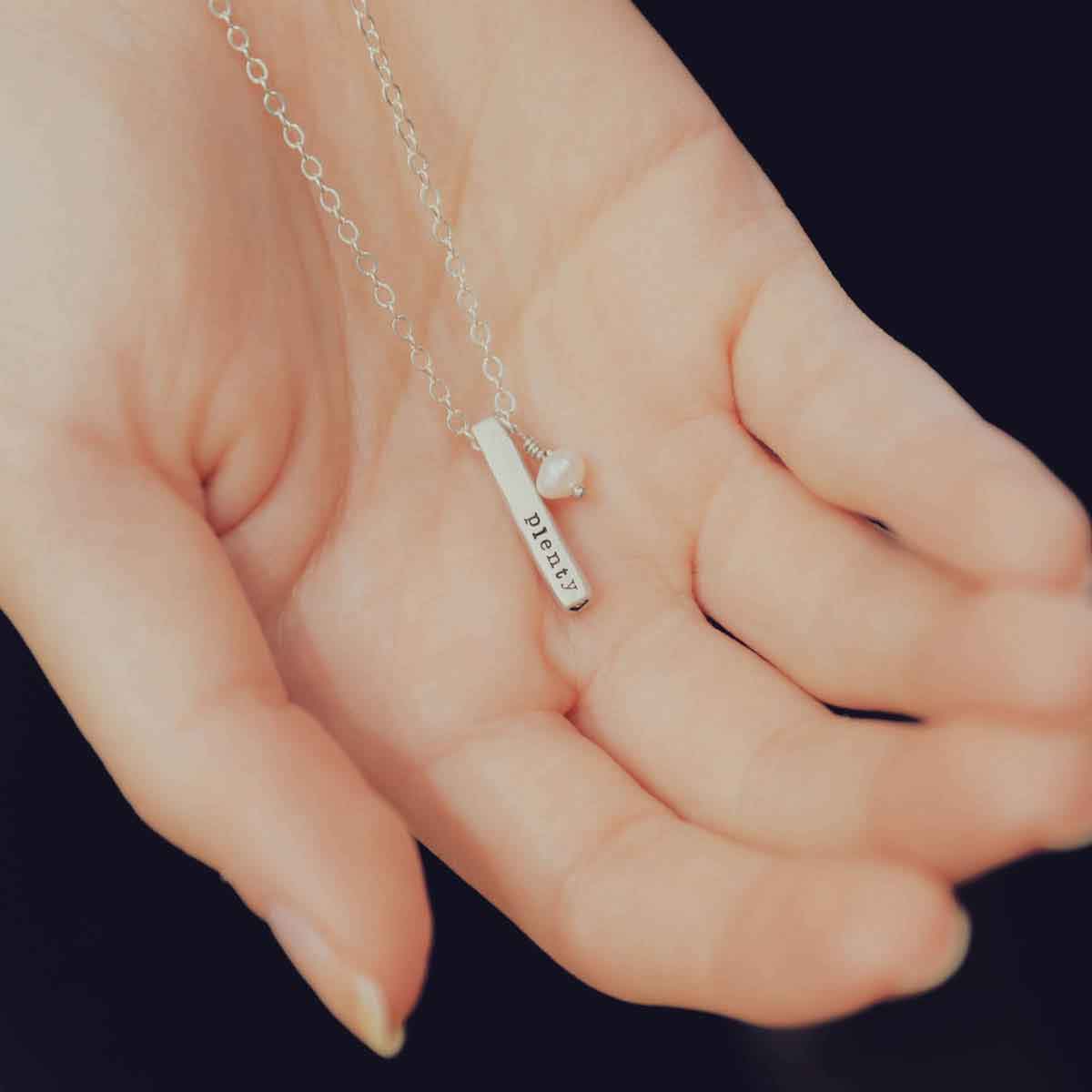 girl holding word of the year necklace in her palm