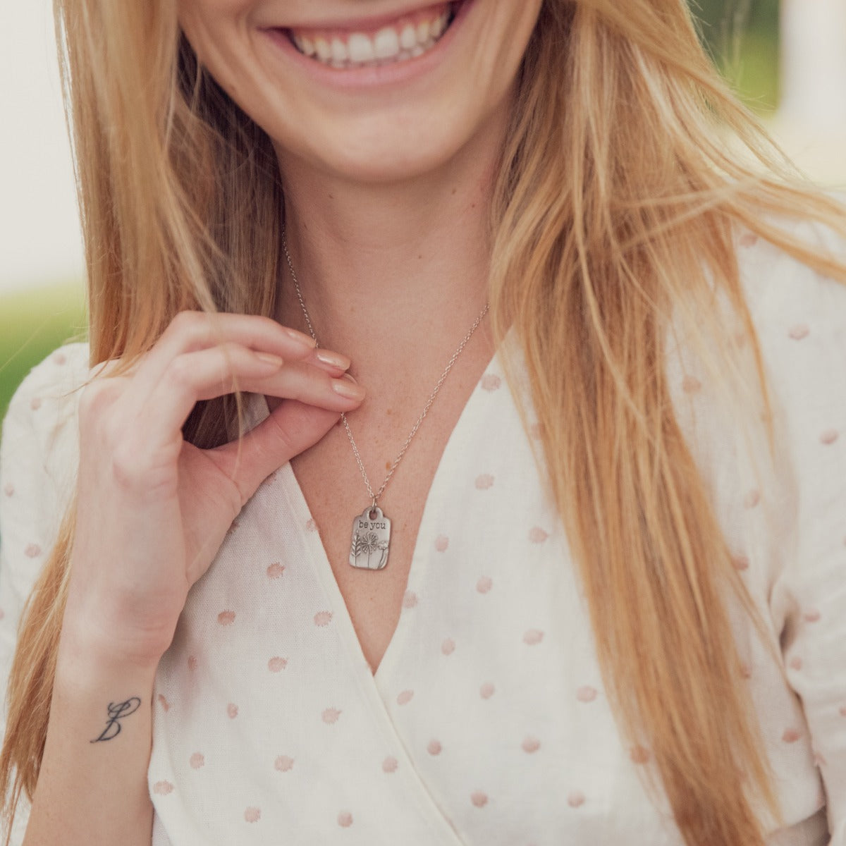 Girl wearing her Be you necklace handcrafted in pewter hung on a silver-toned link chain with the words "be you" engraved