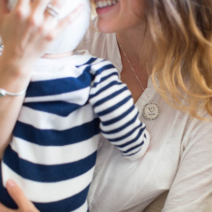 hand holding a sterling silver Mama necklace