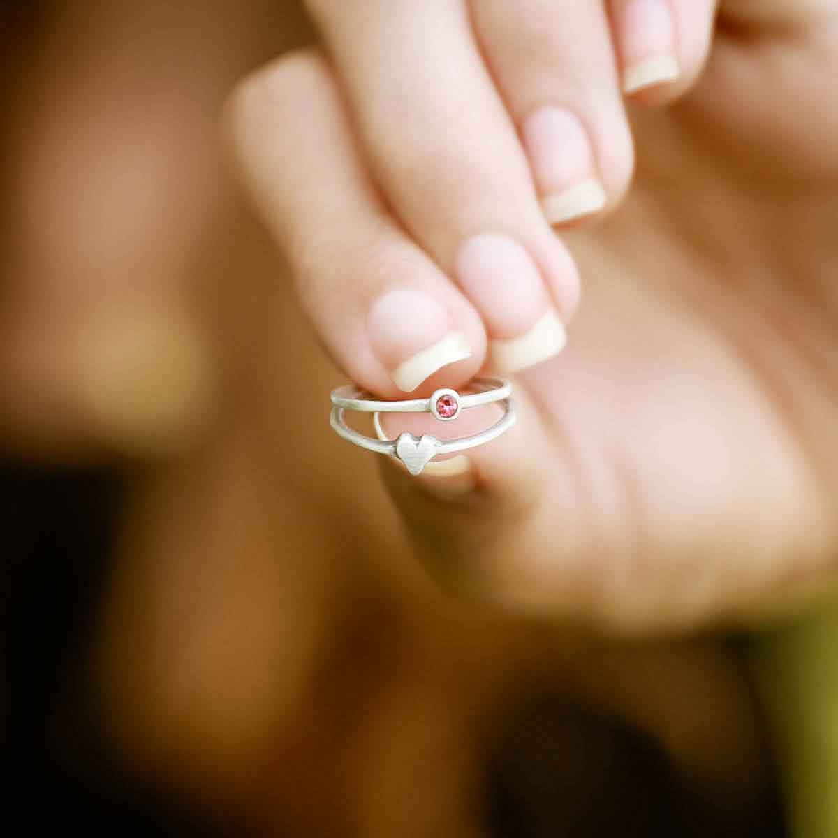 Girl holding love and loss ring pair hand-molded and cast in sterling silver with genuine stones