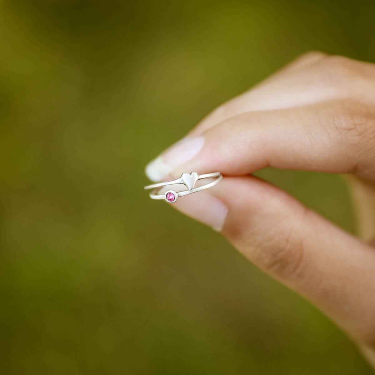 Girl holding love and loss ring pair hand-molded and cast in sterling silver with genuine stones