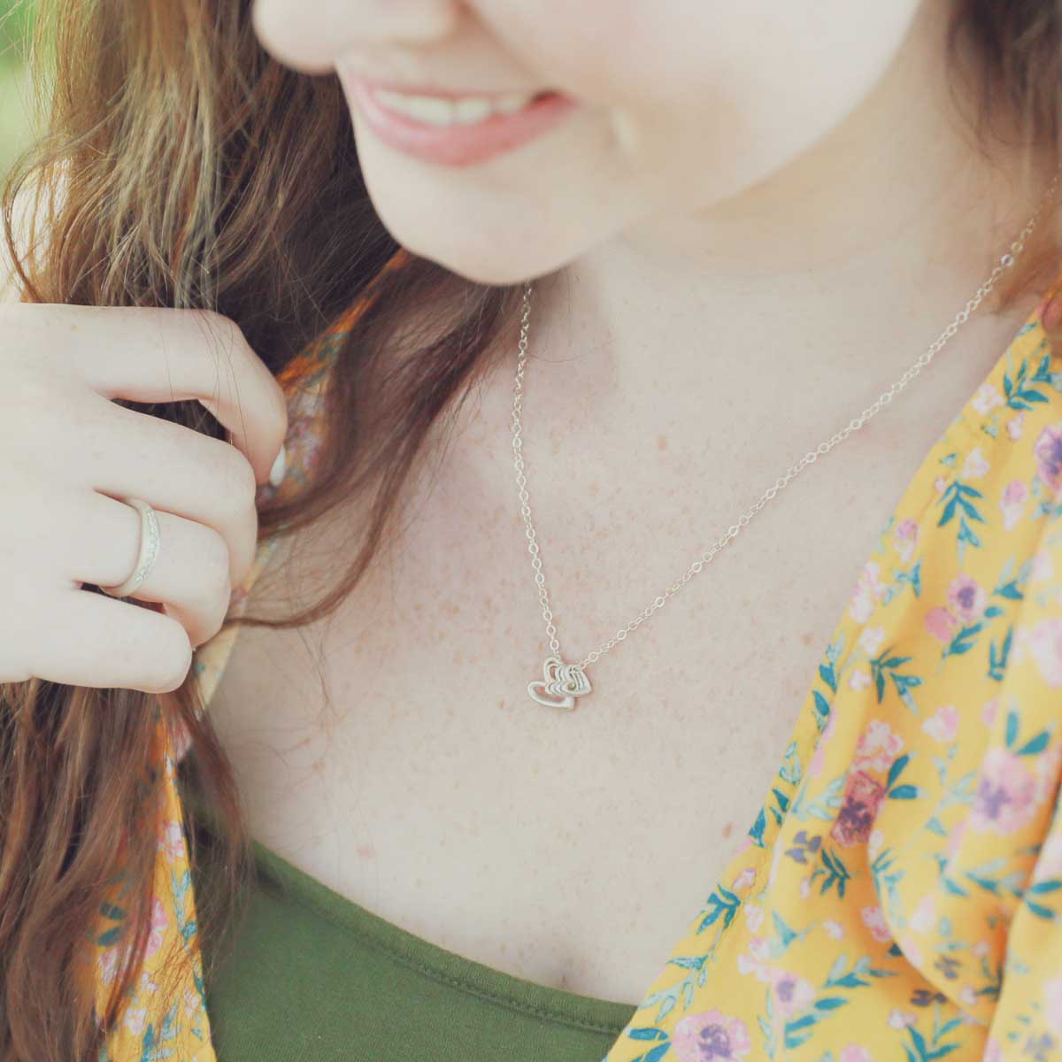 Girl wearing her Love Grows necklace handcrafted in sterling silver with the heart charm strung on sterling silver chain