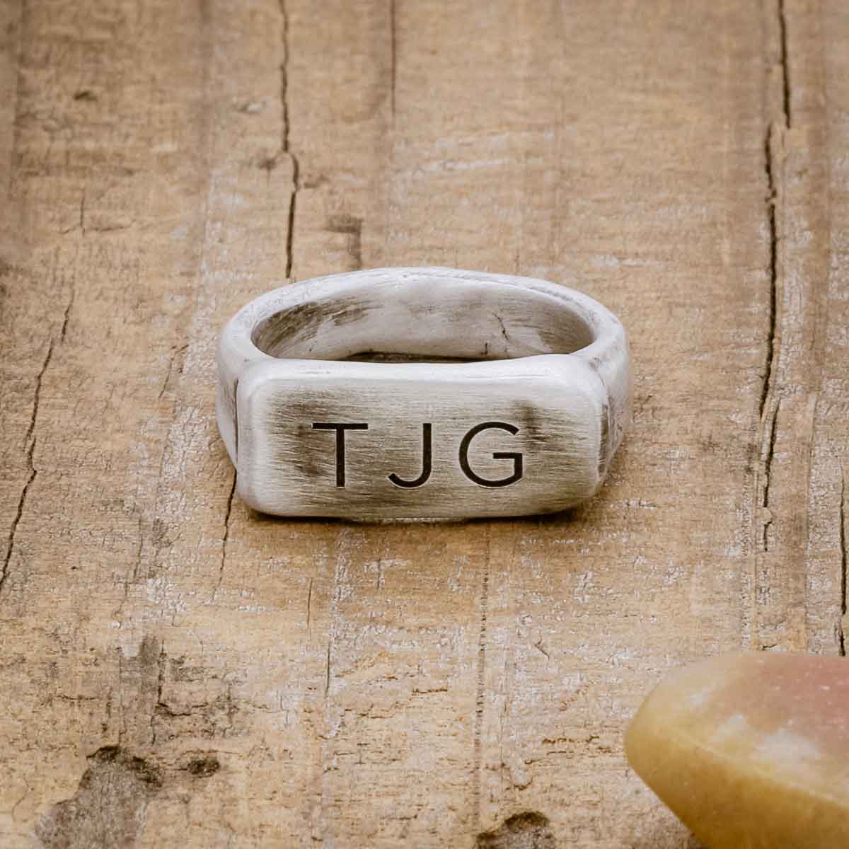 an antiqued sterling silver Make Your Mark Signet ring, personalized with monogram, on wood background