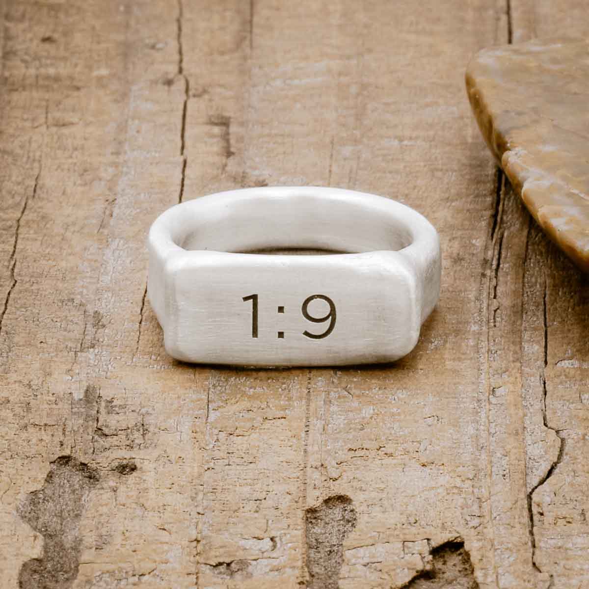 a sterling silver Make Your Mark Signet ring, personalized with numbers, on a wood background