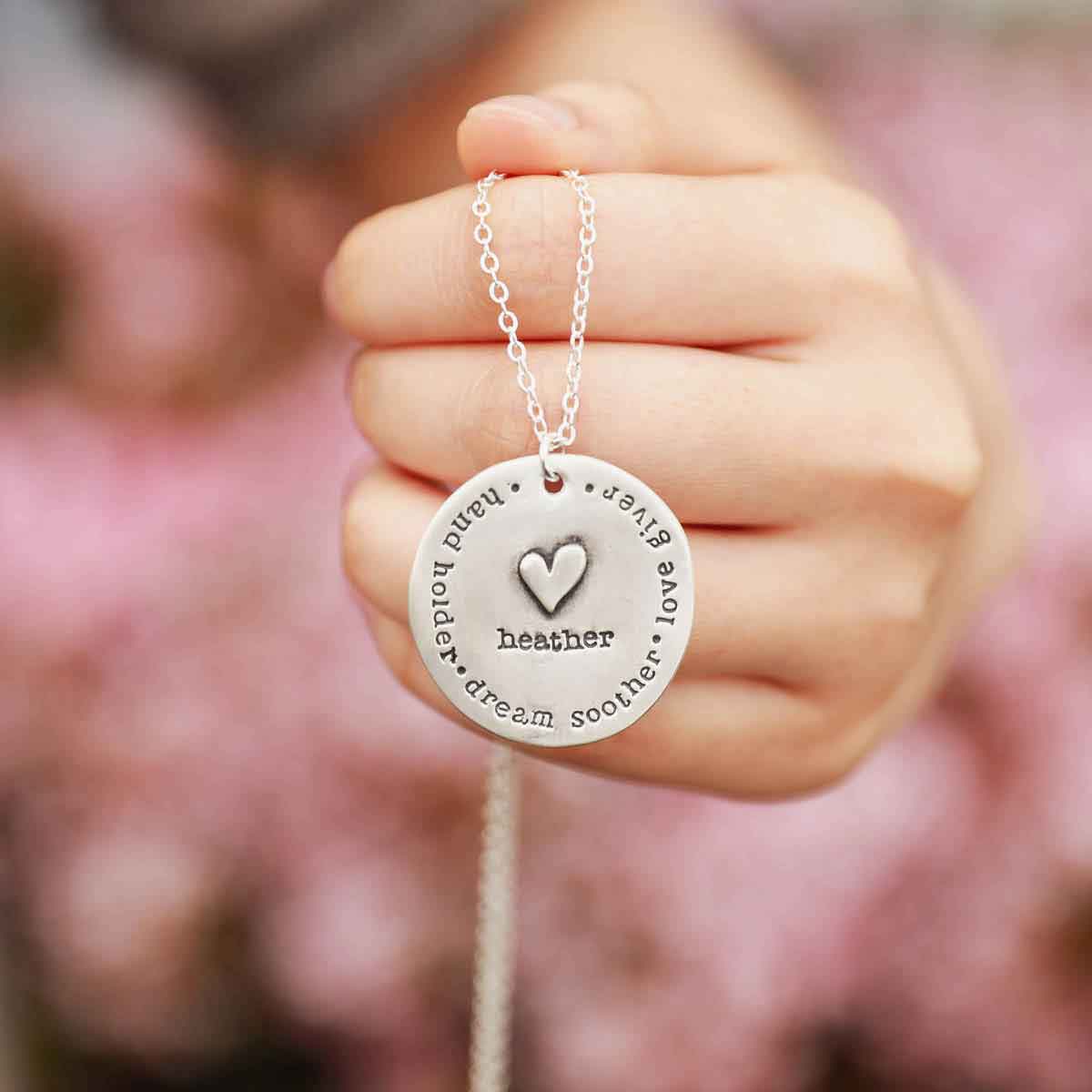 hand holding a sterling silver Mama necklace