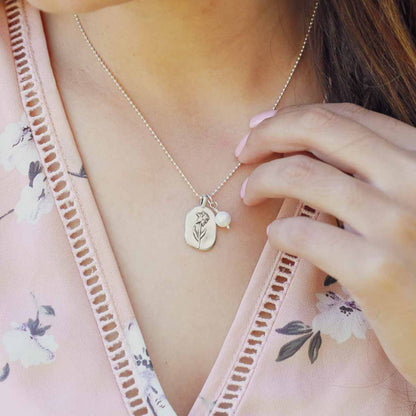 Girl wearing her March birth flower necklace handcrafted in sterling silver with a special birth month charm strung with a vintage freshwater pearl