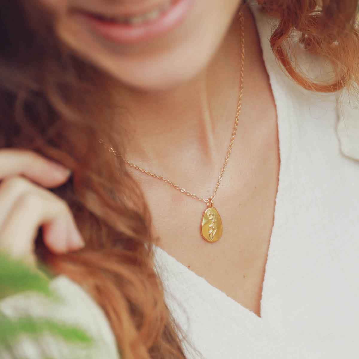 girl holding a gold plated May birth flower necklace with an 18" gold filled link chain