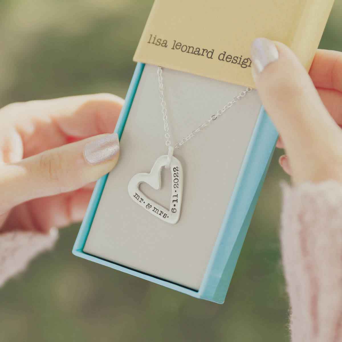 girl holding a sterling silver molded heart necklace with customized personalization