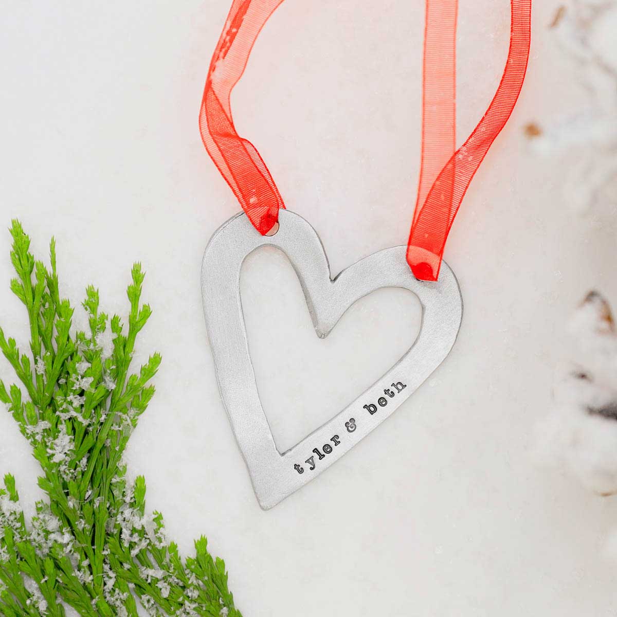 molded heart ornament handcrafted and cast in fine pewter personalized with a meaningful short phrase hanging on a Christmas tree