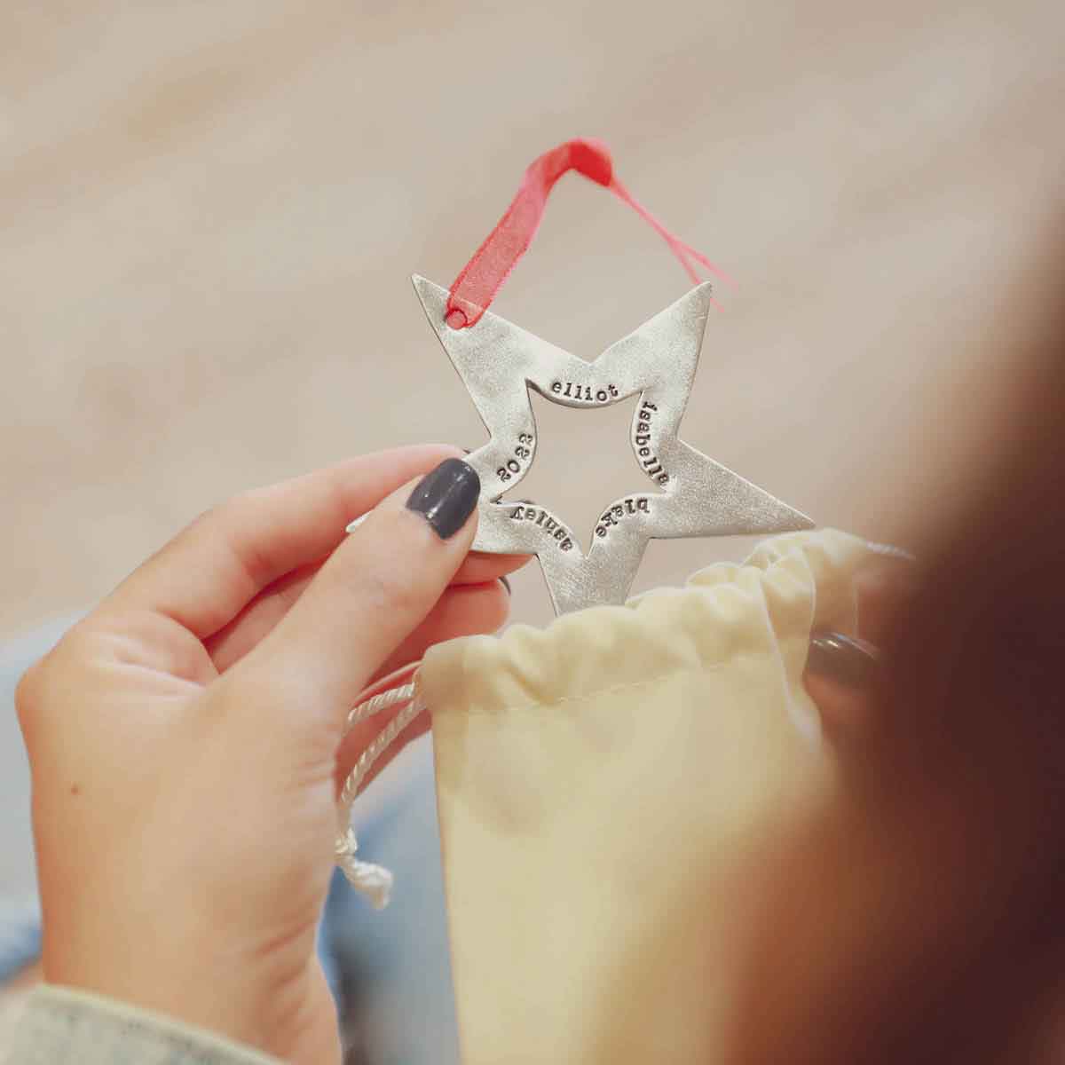 hand hanging a personalized Molded star ornament on Christmas tree