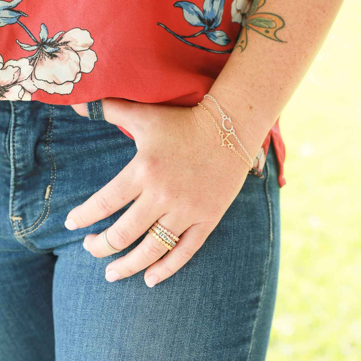 Girl wearing a pair of 10k yellow gold monogram bracelets with a satin finish