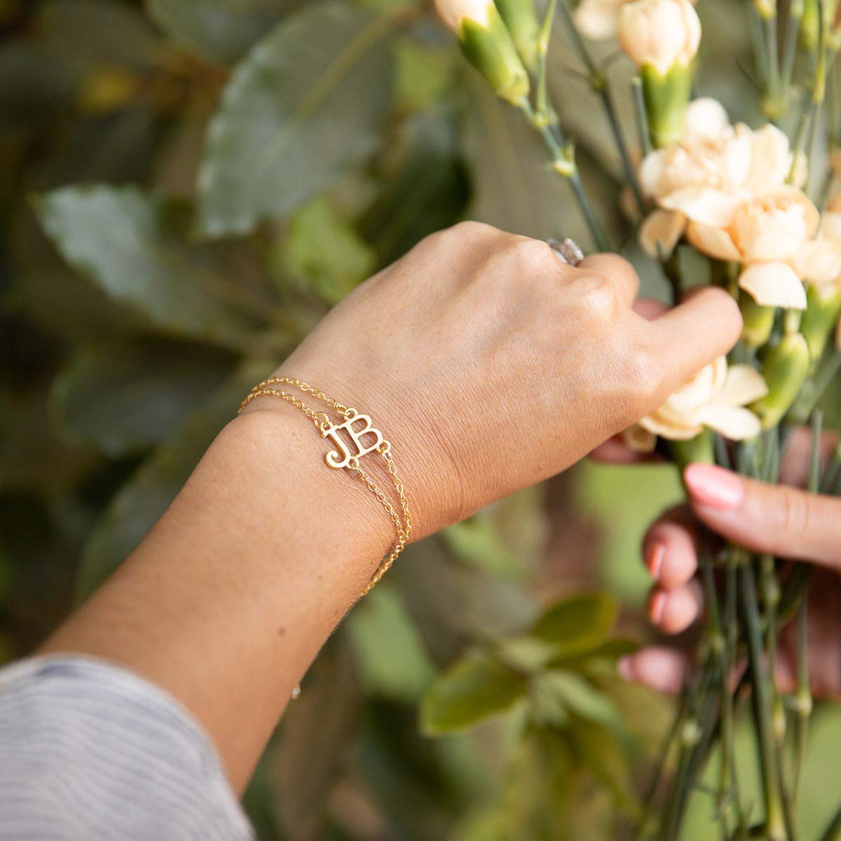 Girl wearing a pair of 10k yellow gold monogram bracelets with a satin finish