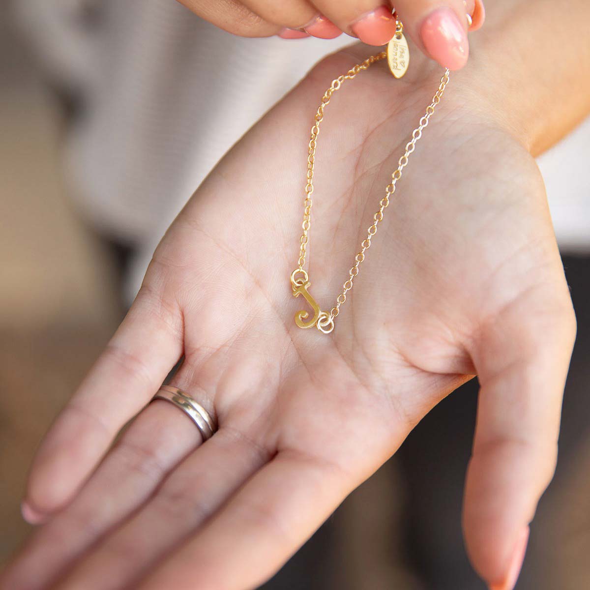 Girl showing her 10k yellow gold monogram bracelet with a satin finish