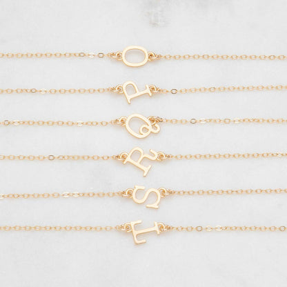 Several 10k yellow gold monogram bracelets with a satin finish going from the letters O to T