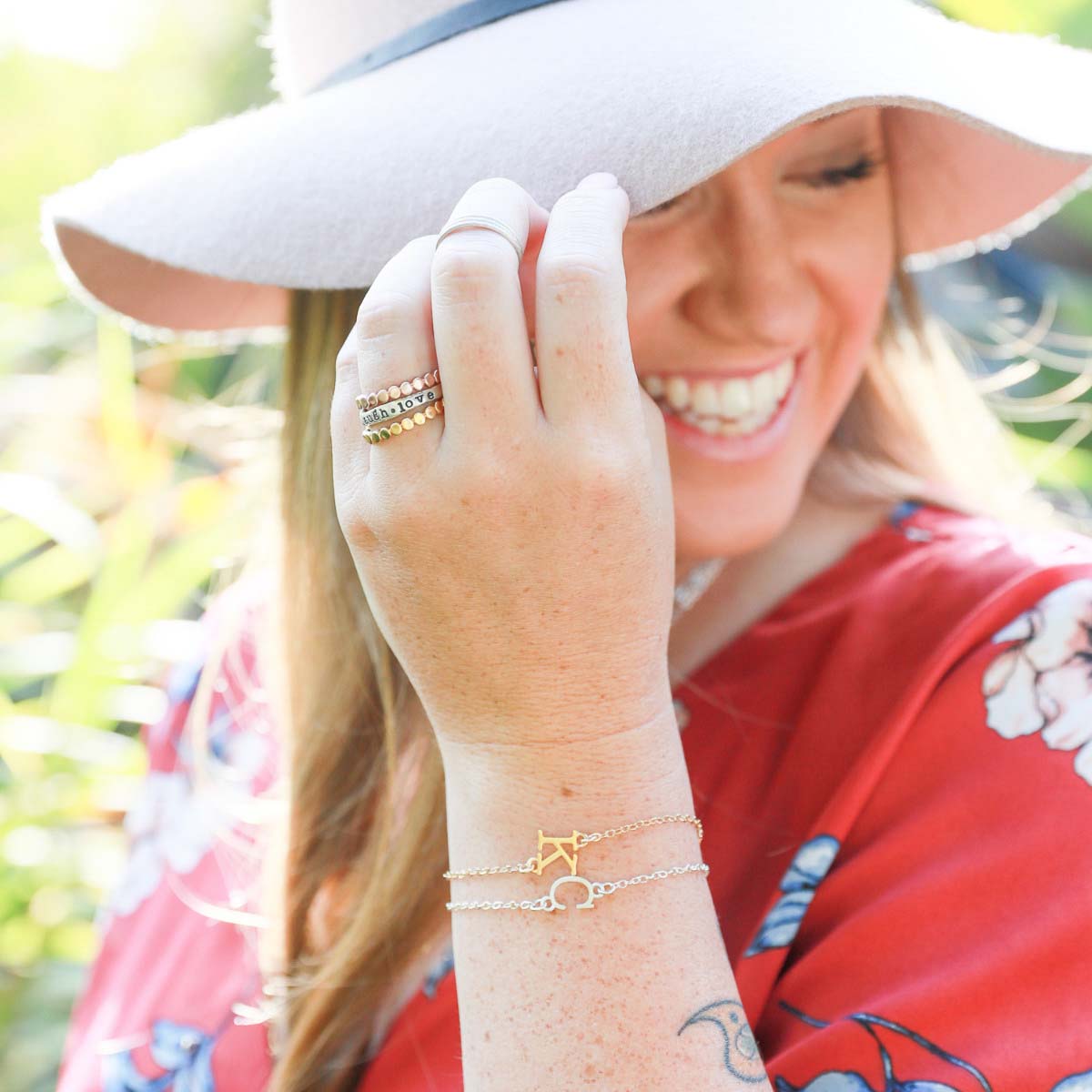 Girl wearing a pair of 10k yellow gold monogram bracelets with a satin finish